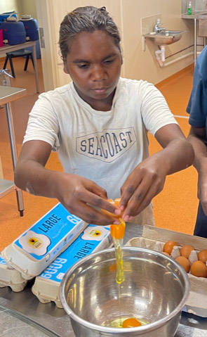 Anna-Lisa Jurra cracking an egg to make scrambled eggs.