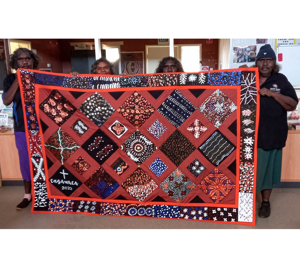 Rachel Tilmouth, Valerie Sharpe, Irene Tilmouth and Patsy Tilmouth holding up the patchwork quilt.