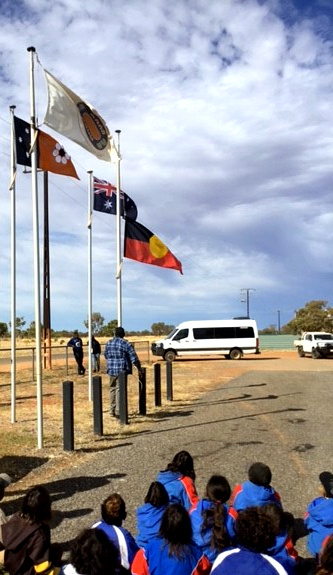 Cr James Glenn raising the Aboriginal flag with the school children watching.